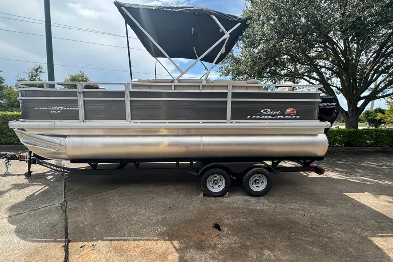 Slide: The Image of 2025 Sun Tracker Fishin' Barge 20 DLX pontoon boat on trailer, parked outdoors. - 55