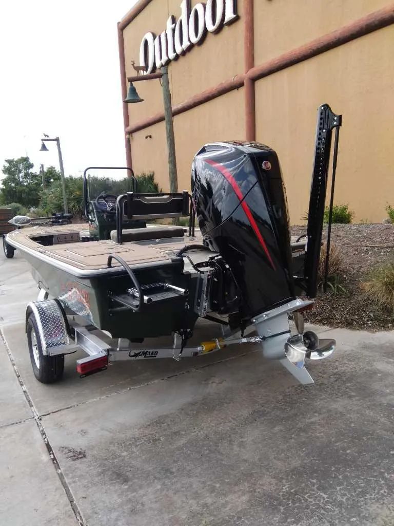 Slide: The Image of 2025 Mako 18 Pro Skiff Backwater Edition boat on trailer outside store. - 5