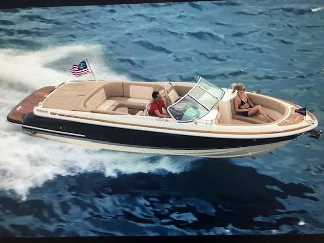 The Image of 2014 Chris-Craft Launch 25 boat cruising on open water with passengers. - 0