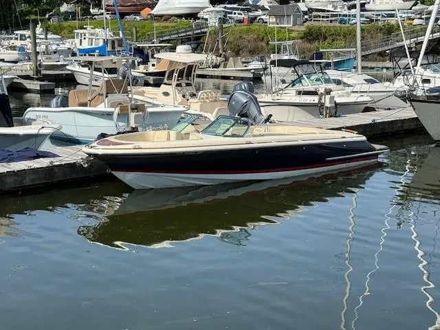 Slide: The Image of 2014 Chris-Craft Launch 25 boat docked in a marina, surrounded by other vessels. - 2