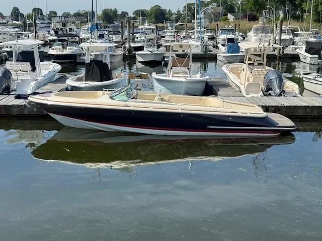 Slide: The Image of 2014 Chris-Craft Launch 25 boat docked in a marina, surrounded by other vessels. - 4