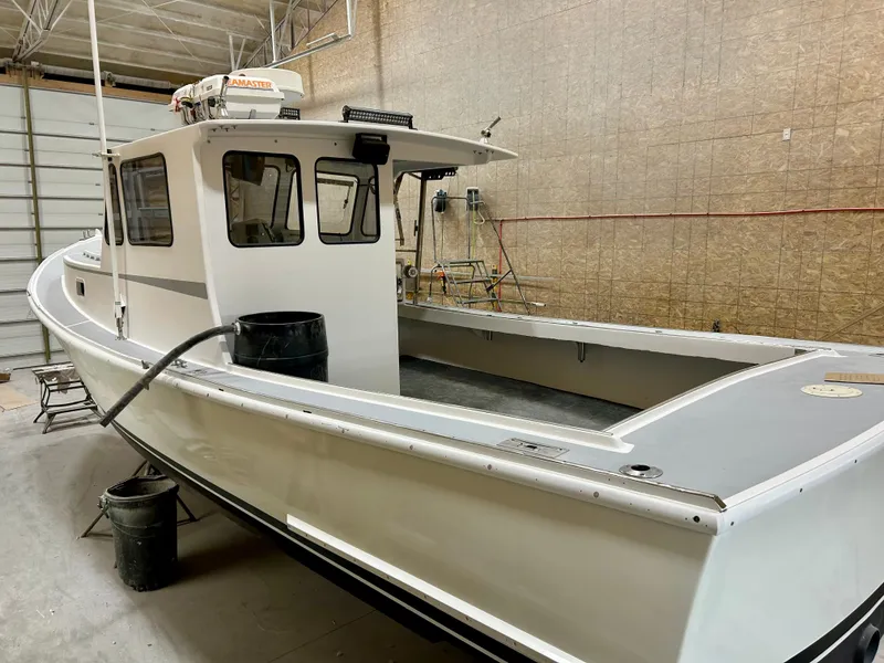Slide: The Image of 1980 Holland 32 boat in a workshop, white exterior, spacious deck, enclosed cabin. - 12
