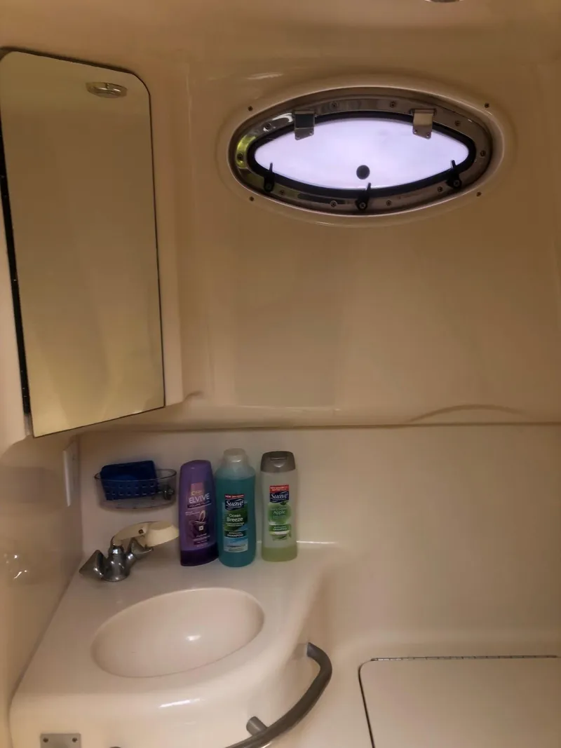 Slide: The Image of Bathroom interior of 1998 Sea Ray 290 Sundancer with sink, toiletries, and porthole window. - 12