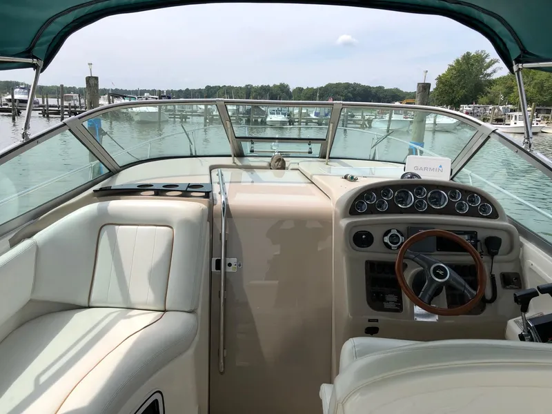 Slide: The Image of 1998 Sea Ray 290 Sundancer boat cockpit with steering wheel and dashboard, docked at marina. - 3