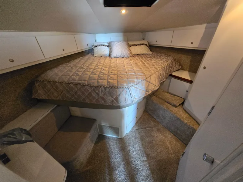 Slide: The Image of 1996 Silverton 37 Convertible cabin interior with bed, storage cabinets, and carpeted flooring. - 11