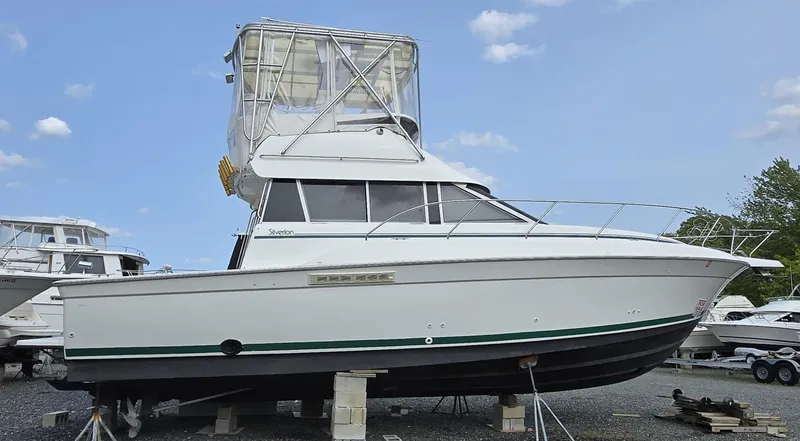 Slide: The Image of 1996 Silverton 37 Convertible boat on dry dock, white exterior, clear sky background. - 21