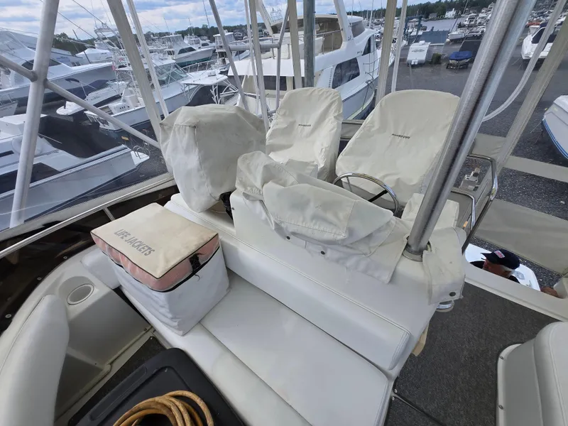 Slide: The Image of 1996 Silverton 37 Convertible boat interior with covered seats and marina view. - 37