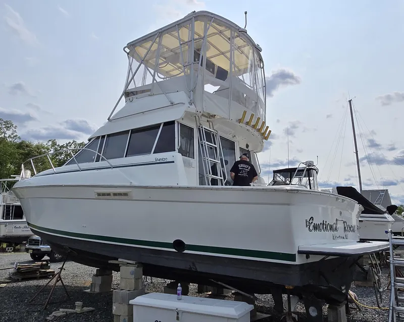 Slide: The Image of 1996 Silverton 37 Convertible boat on dry dock, featuring a spacious flybridge and white exterior. - 50