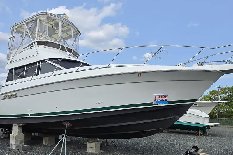 Slide: The Image of 1996 Silverton 37 Convertible boat for sale, elevated on blocks, under a clear blue sky. - 51