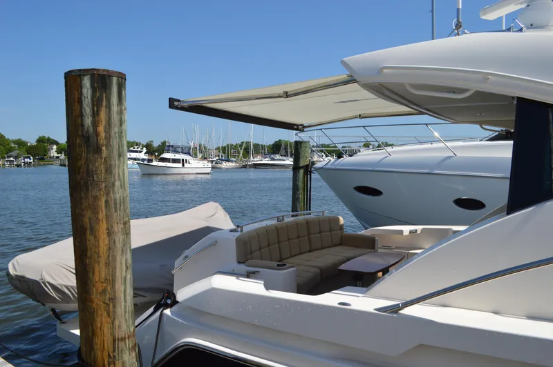 Slide: The Image of 2016 Tiara Yachts C44 Coupe docked, featuring spacious seating and scenic marina view. - 17