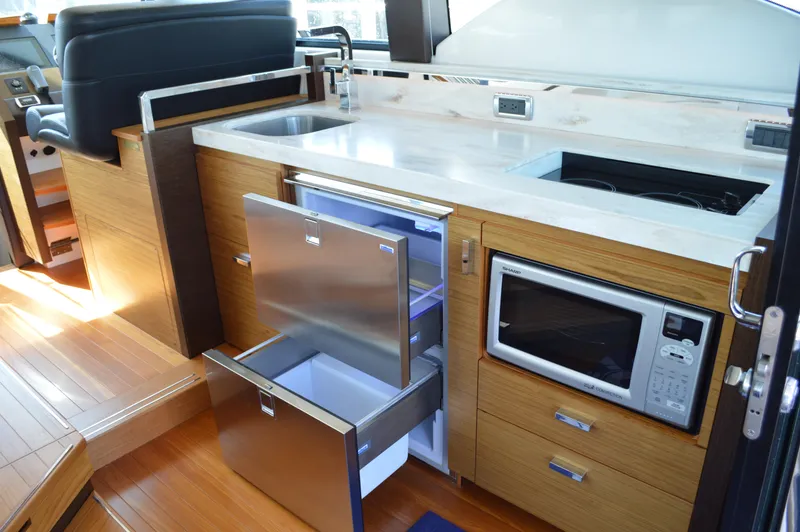 Slide: The Image of 2016 Tiara Yachts C44 Coupe interior kitchen with sink, fridge, and microwave. - 45
