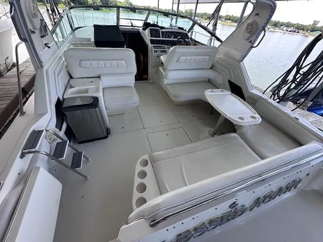 Slide: The Image of 1995 Sea Ray 400 Express Cruiser interior with white seating and helm, docked by the water. - 5