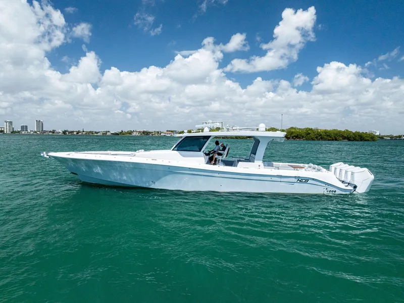 Slide: The Image of 2025 HCB 56' Sueños GIX luxury yacht cruising on clear blue water under a partly cloudy sky. - 5