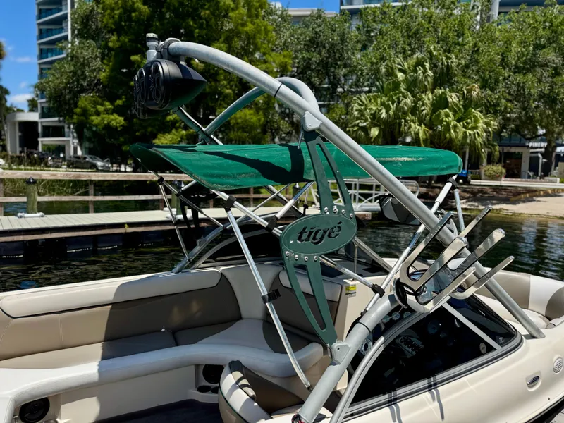 Slide: The Image of 2005 Tigé 24V boat with wakeboard tower and green canopy, docked by lush greenery. - 12