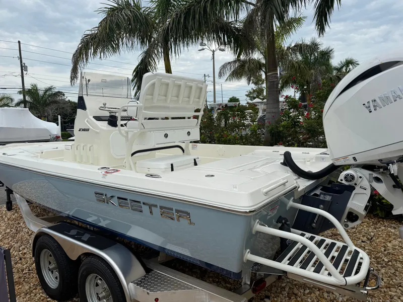 Slide: The Image of 2025 Skeeter SX 221 boat with Yamaha engine, parked on a trailer, surrounded by palm trees. - 16