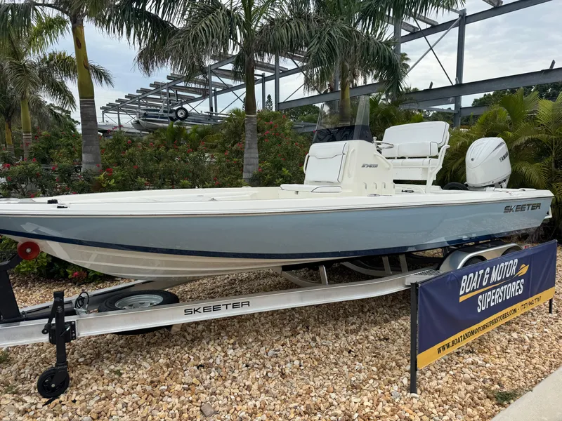 Slide: The Image of 2025 Skeeter SX 221 boat on display at dealership, surrounded by tropical plants. - 2