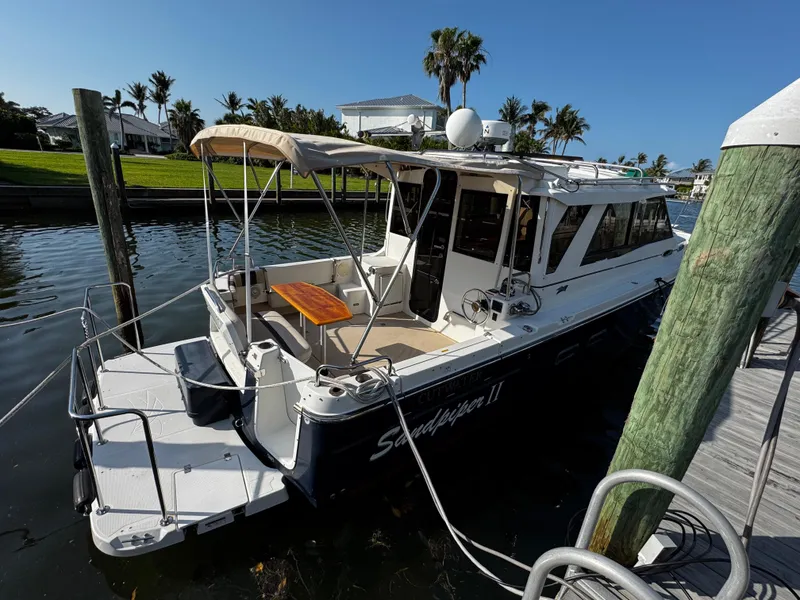 The Image of 2014 Cutwater 30 Sedan LE docked, featuring spacious deck and canopy, surrounded by palm trees. - 0