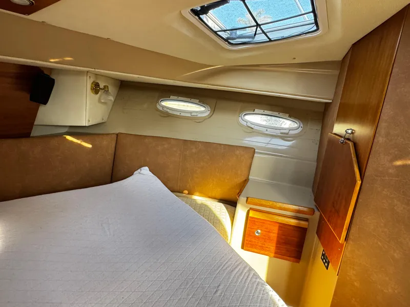 Slide: The Image of 2014 Cutwater 30 Sedan LE cabin interior with bed, portholes, and wooden cabinetry. - 18