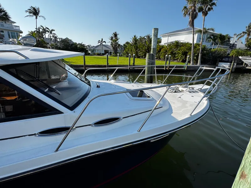 Slide: The Image of 2014 Cutwater 30 Sedan LE docked by waterfront homes, sunny day. - 2