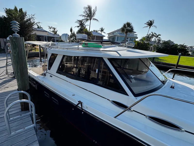 Slide: The Image of 2014 Cutwater 30 Sedan LE docked near palm trees and waterfront homes. - 3