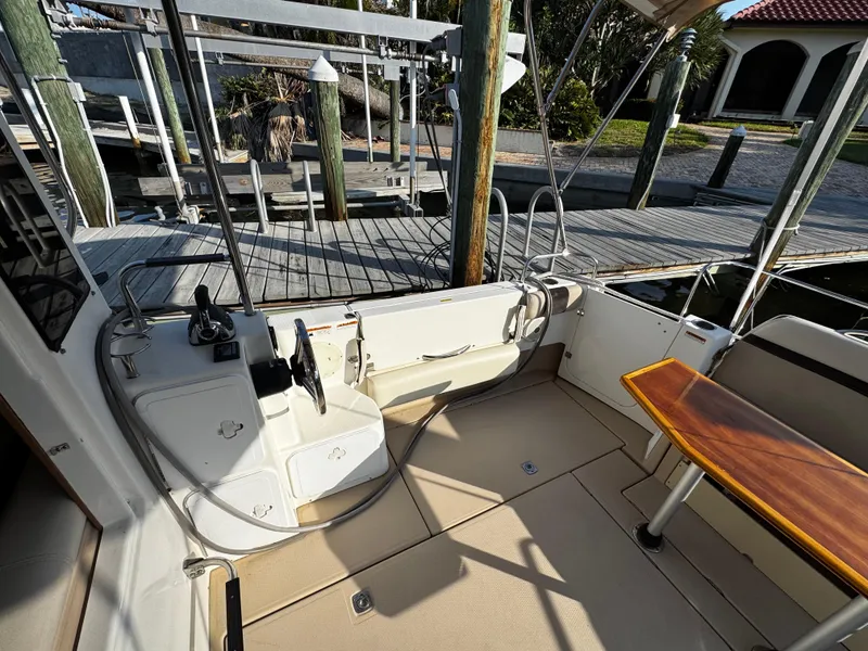 Slide: The Image of 2014 Cutwater 30 Sedan LE boat interior with helm, seating, and wooden table at dock. - 5