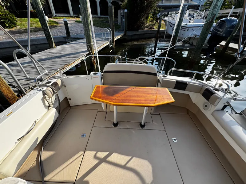 Slide: The Image of 2014 Cutwater 30 Sedan LE boat interior with wooden table and seating at dock. - 7