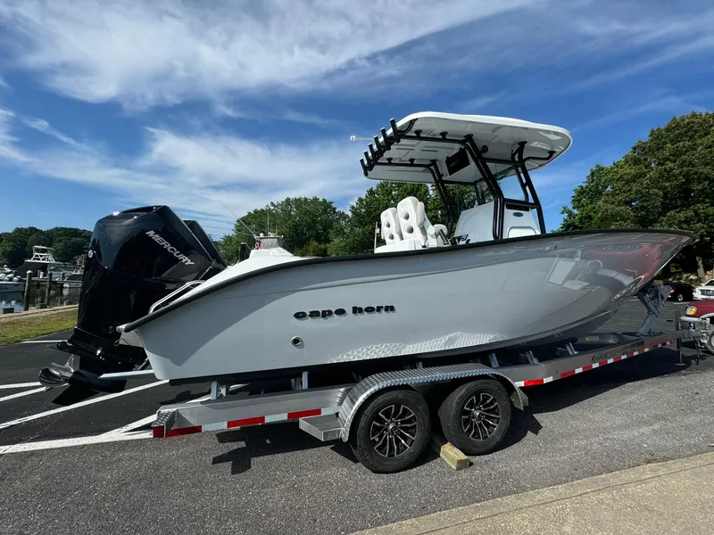 Slide: The Image of 2025 Cape Horn 27 XS boat on trailer, parked outdoors under a clear blue sky. - 2