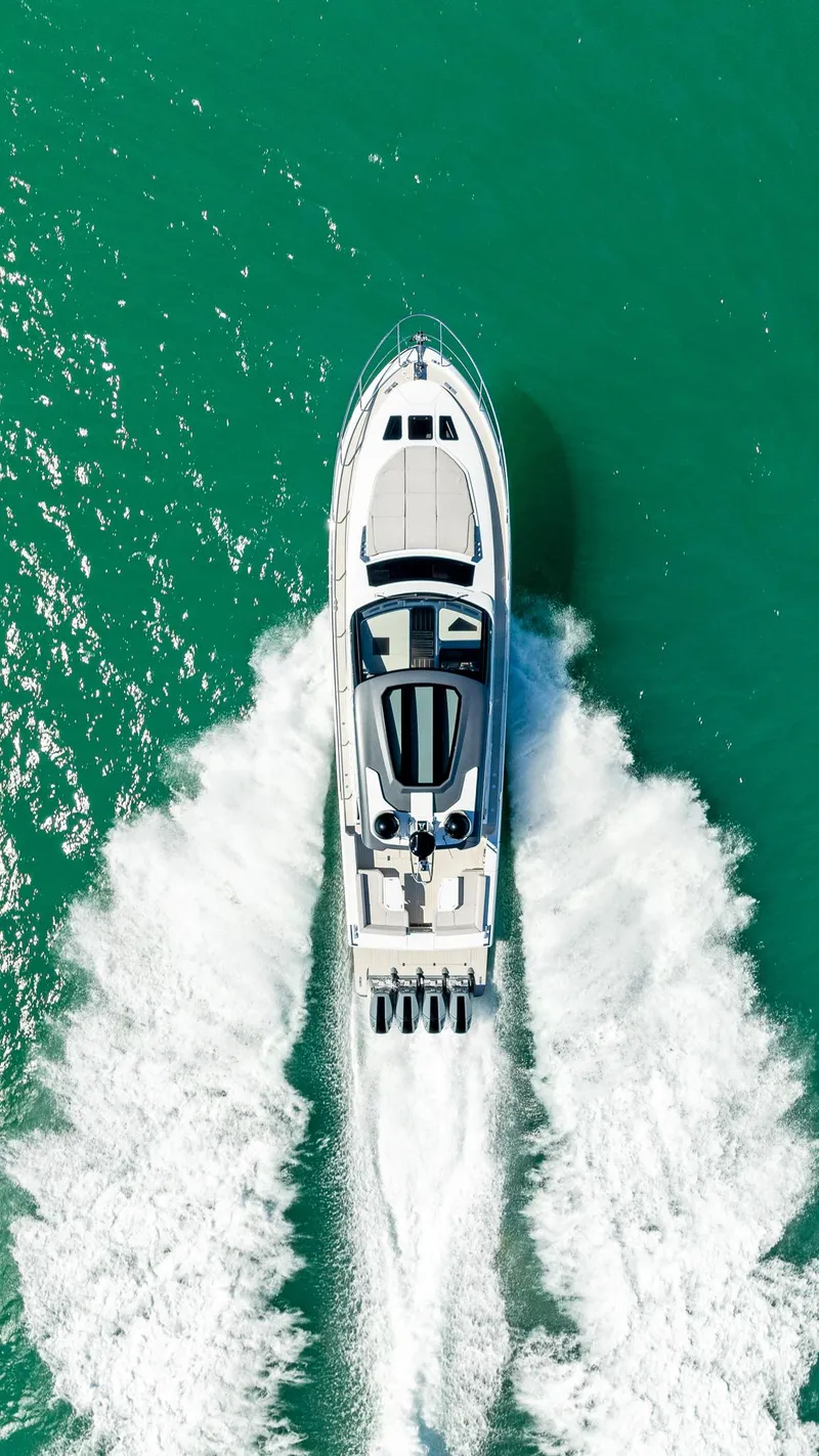 Slide: The Image of 2024 Uniesse Exuma HTC5p yacht cruising on turquoise water, aerial view. - 1