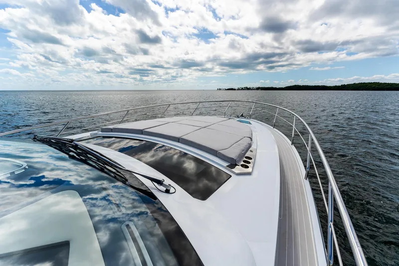 Slide: The Image of 2024 Uniesse Exuma HTC5p yacht cruising on open water under a partly cloudy sky. - 10