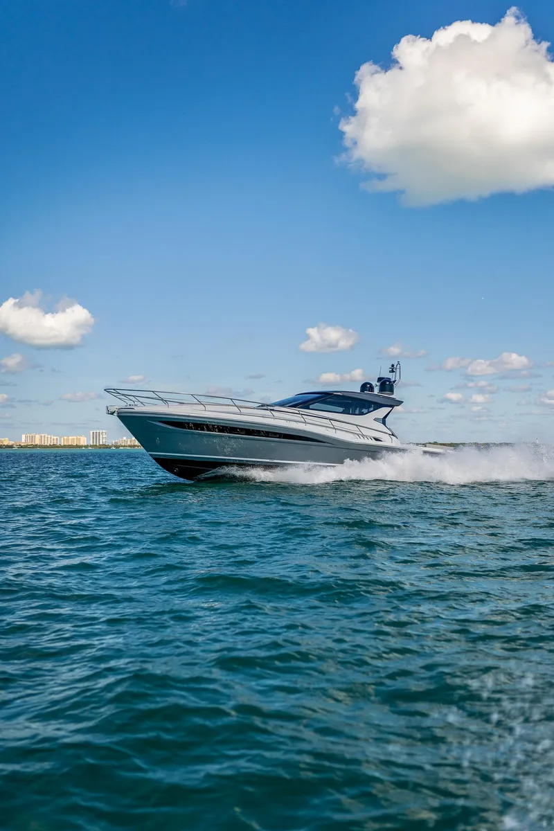 Slide: The Image of 2024 Uniesse Exuma HTC5p yacht cruising on open water under a clear blue sky. - 2