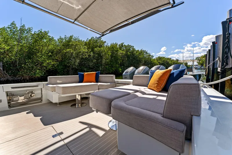 Slide: The Image of 2024 Uniesse Exuma HTC5p yacht deck with modern seating and canopy, surrounded by lush greenery. - 39