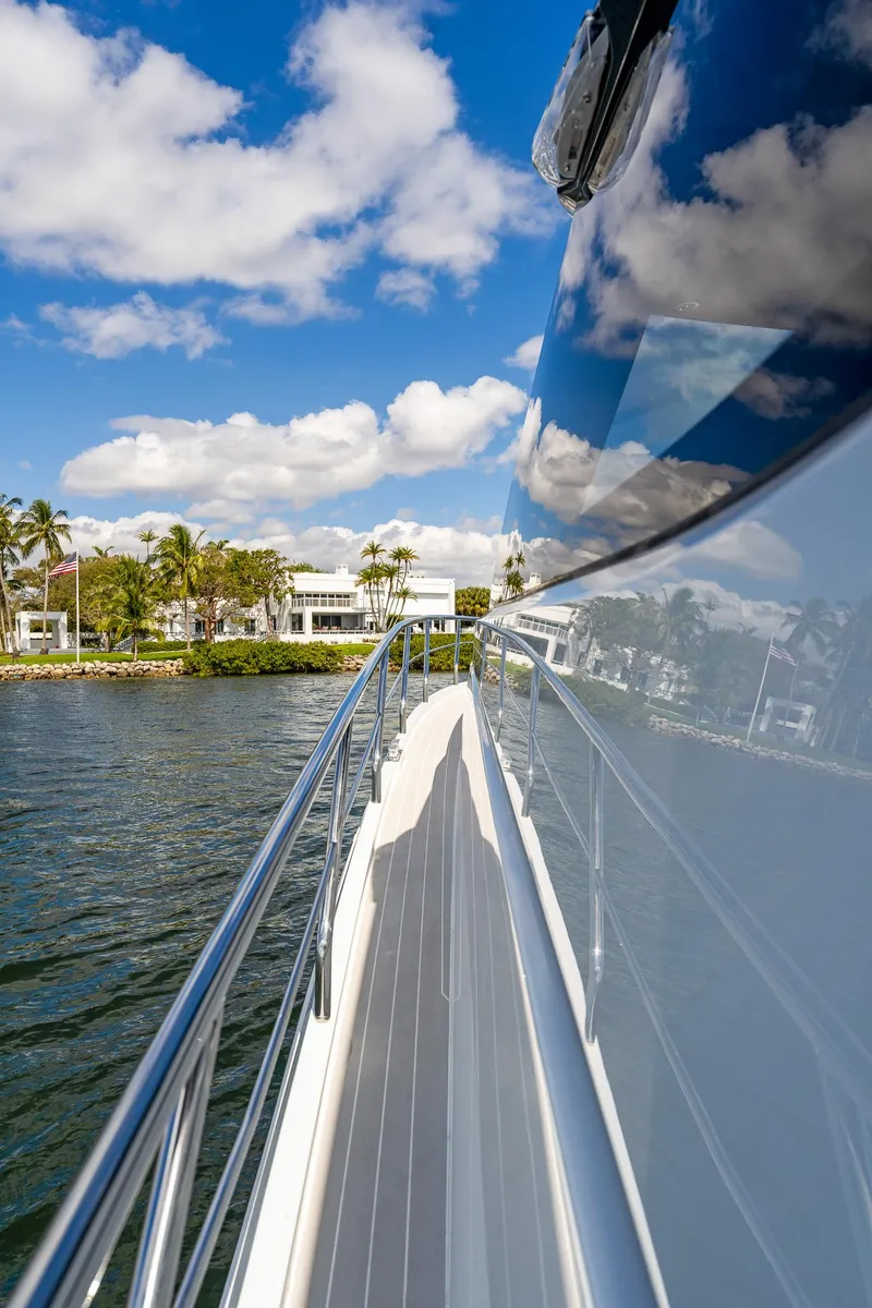 Slide: The Image of 2024 Uniesse Exuma HTC5p yacht reflecting water and sky, cruising near luxury waterfront homes. - 8