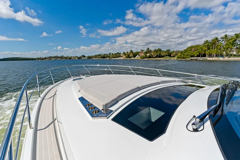 Slide: The Image of 2024 Uniesse Exuma HTC5p yacht cruising on a sunny day near a tropical shoreline. - 9