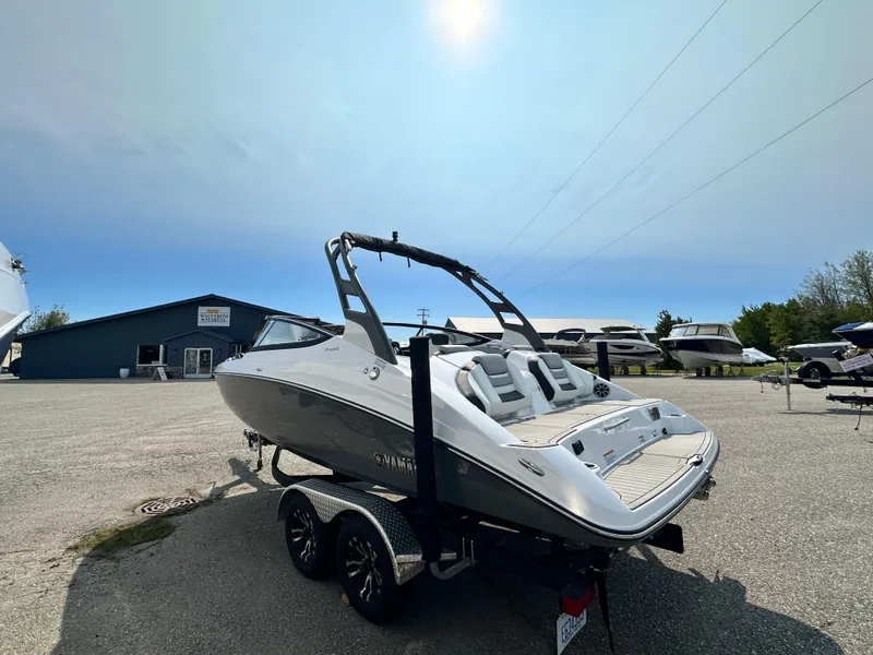 Slide: The Image of 2022 Yamaha Boats 212SD on trailer under clear sky at marina. - 20