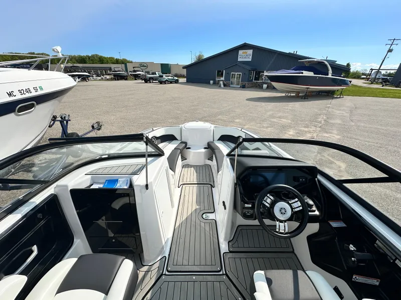 Slide: The Image of 2022 Yamaha Boats 212SD interior with sleek design and modern dashboard in a marina setting. - 5