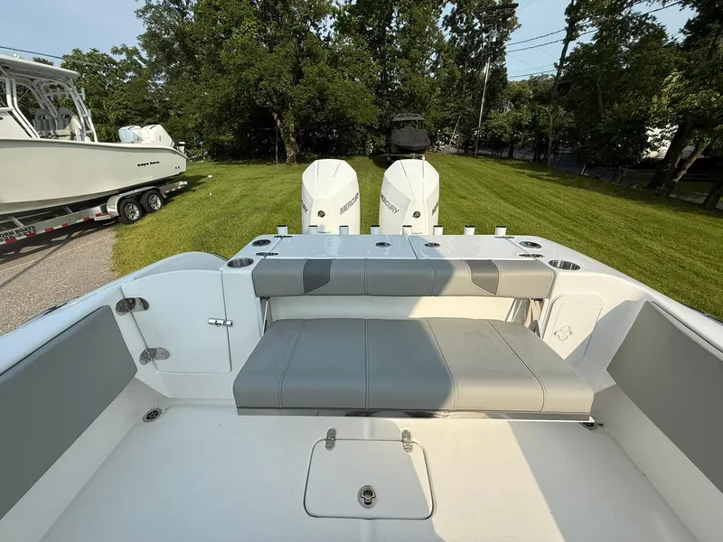 Slide: The Image of 2025 Cape Horn 32 XS boat with dual engines and cushioned seating, parked on grass. - 9