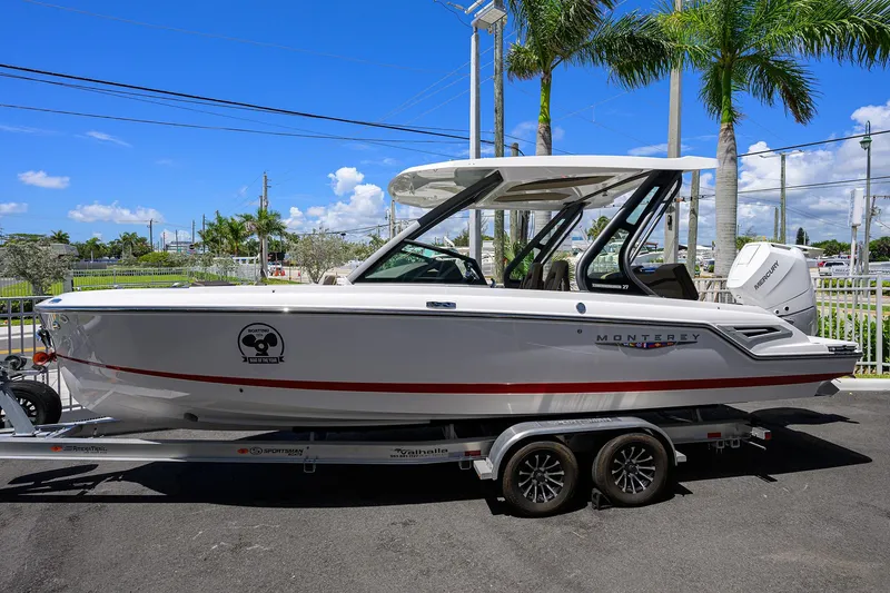 The Image of 2026 Monterey Elite 27 OB boat on trailer, parked under clear blue sky. - 1