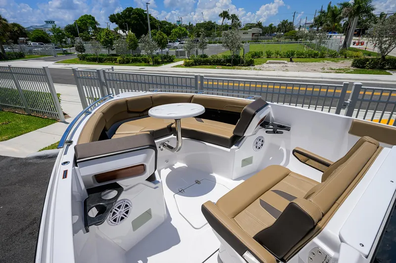 Slide: The Image of 2026 Monterey Elite 27 OB boat interior with tan seating and table, docked near a fence. - 18