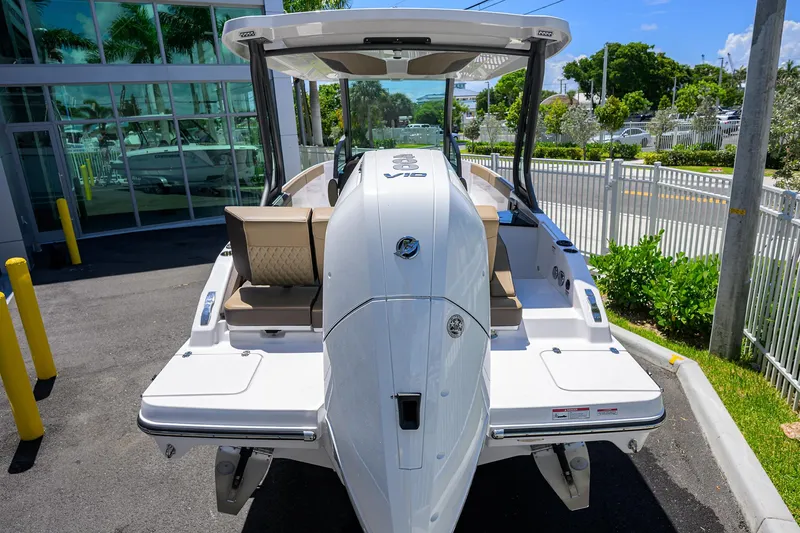 Slide: The Image of 2026 Monterey Elite 27 OB boat, rear view, parked outdoors near a modern building. - 23