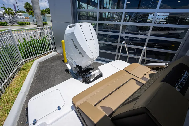 Slide: The Image of 2026 Monterey Elite 27 OB boat with Mercury outboard engine, parked near a modern building. - 24