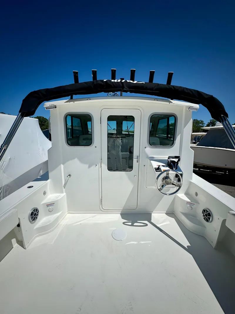 Slide: The Image of 2025 Parker 2820 XLD Sport Cabin boat with spacious deck and cabin under clear blue sky. - 7
