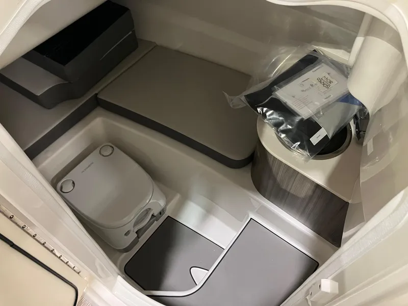 Slide: The Image of 2025 Sea Ray SDX 250 boat interior with compact toilet and storage area. - 8