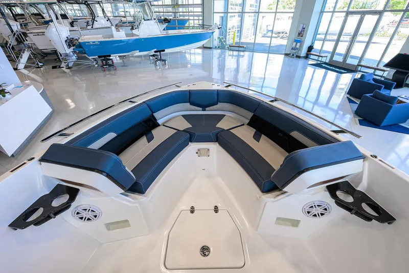 Slide: The Image of 2026 Monterey Elite 27 OB boat interior with blue seating and cup holders in showroom. - 19