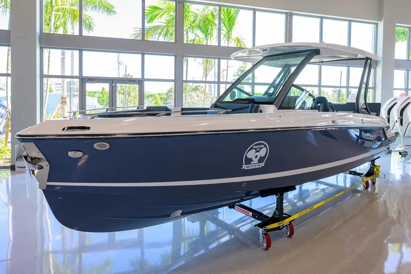 Slide: The Image of 2026 Monterey Elite 27 OB boat displayed indoors with large windows and palm trees outside. - 3