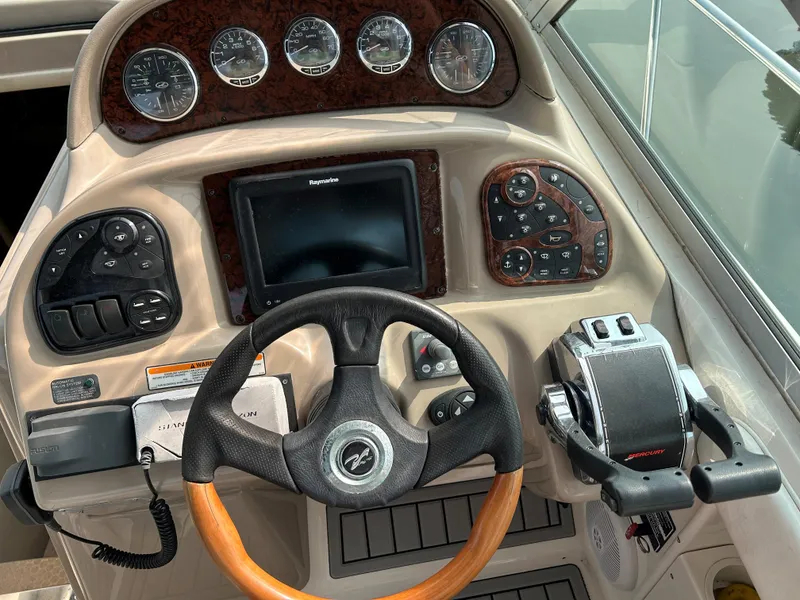 Slide: The Image of Dashboard of a 2005 Sea Ray 300 Sundancer boat with steering wheel and controls. - 10
