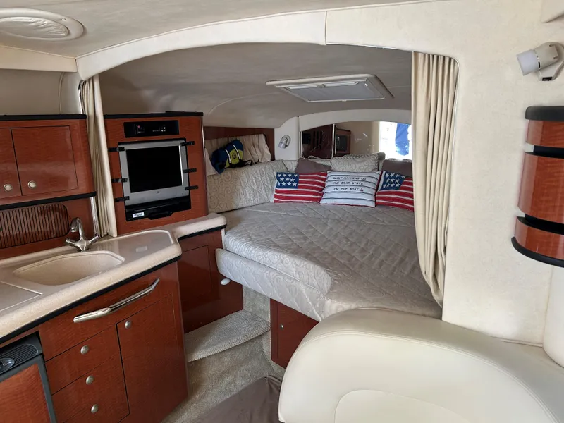 Slide: The Image of 2005 Sea Ray 300 Sundancer cabin interior with bed, kitchenette, and American flag pillows. - 13