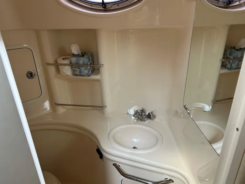 Slide: The Image of 2005 Sea Ray 300 Sundancer bathroom with sink, mirror, and storage shelves. - 15