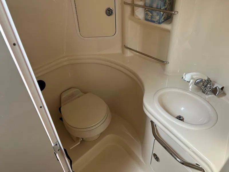 Slide: The Image of 2005 Sea Ray 300 Sundancer bathroom with toilet, sink, and storage shelves. - 16