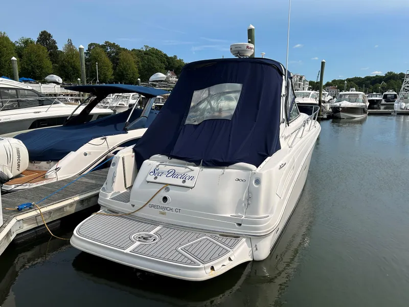 Slide: The Image of 2005 Sea Ray 300 Sundancer docked in marina, rear view with blue cover. - 2