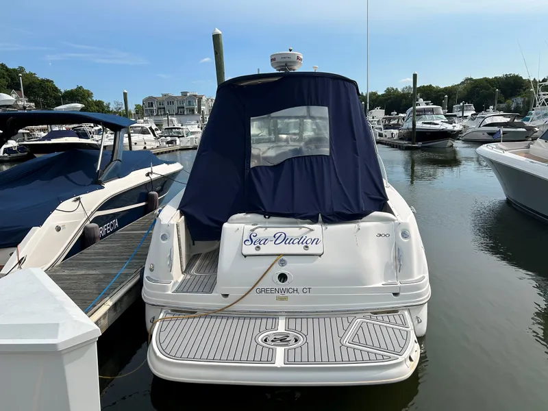 Slide: The Image of 2005 Sea Ray 300 Sundancer docked at marina, rear view with blue cover. - 3